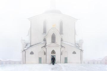 A person walking towards Pilgrimage Church of St. John of Nepomuk at Zelena hora, Zdar nad Sazavou (Žďár nad Sázavou in czech language) in winter weather.