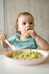 one girl small caucasian child one year old eat at the table at home