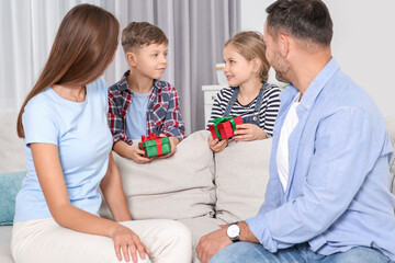 Little children presenting their parents with gifts at home