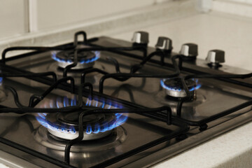 Gas cooktop with burning blue flames, closeup