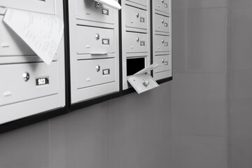 Closed grey metal mailboxes with receipts indoors