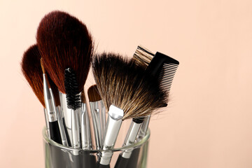 Set of professional makeup brushes against beige background, closeup