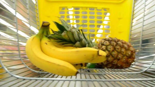 The cart in a supermarket. Bananas and pineapple are