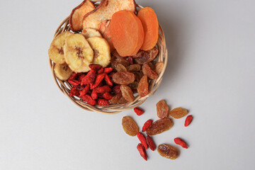 Wicker basket with different dried fruits on white background, top view