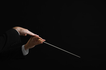 Professional conductor with baton on black background, closeup. Space for text