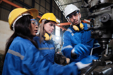 Fototapeta premium An Industrial workers team in protective and safety uniforms and hardhats, male manager, and female colleagues work with metalwork machines in manufacturing factory. Professional production engineer.