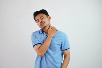 A portrait of young Asian man having has neck and shoulder pain wearing blue t shirt isolated on white background