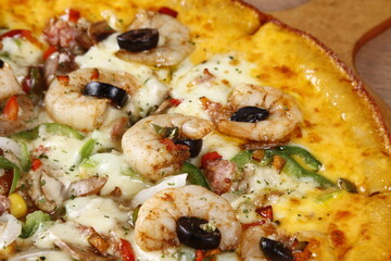 Cheesy seafood pizza with shrimp, bacon, olives, bell peppers, tomato