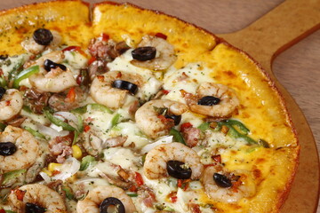 Cheesy seafood pizza with shrimp, bacon, olives, bell peppers, tomato