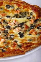 Cheesy seafood pizza with shrimp, bacon, olives, bell peppers, tomato