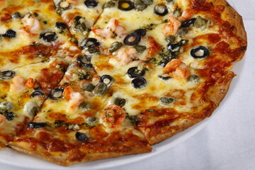 Cheesy seafood pizza with shrimp, bacon, olives, bell peppers, tomato