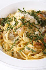 Closeup of creamy carbonara with shredded greens and parmesan cheese