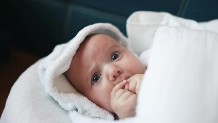 infant girl a newborn sucking thumb. happy family kid dream concept. close up cute newborn baby wrapped in bath towel at home indoors. daughter a small child sucks his thumb lifestyle after bathing