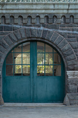 Fototapeta na wymiar Arched Doors with Faded Teal Paint and a Gothic Architecture Stone Wall.