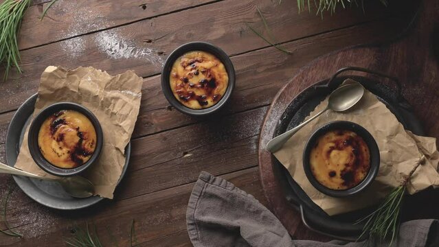 Creme brulee. Bowls with French vanilla cream dessert with caramelised sugar on top, spoons, dark rustic table.