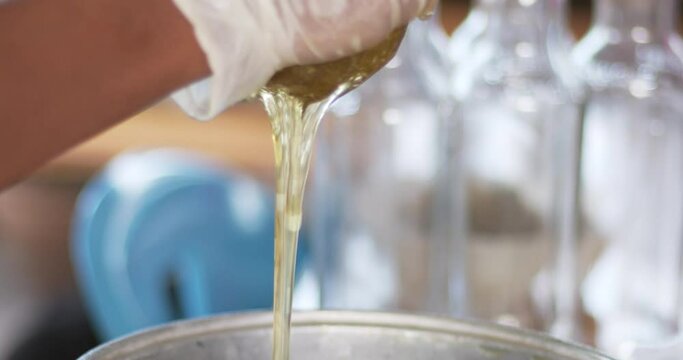 Close-up shot of honey filtered from a clean cheesecloth into a barrel.