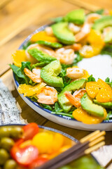 Green healthy vegan salad with arugula, avocado, shrimps and tangerines