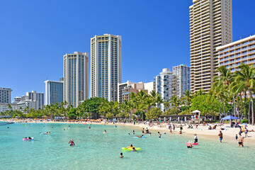 Tourists enjoying the warm sunny weather at Kuhio Beach in Waikiki area of Honolulu on Oahu, Hawaii