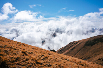 Grassy slopes in the mountains of the Greater Caucasus. In the foreground high orange grass and in...