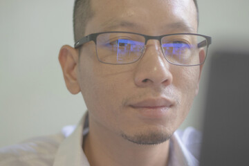 Young businessman in eyeglasses sitting and working on laptop screen