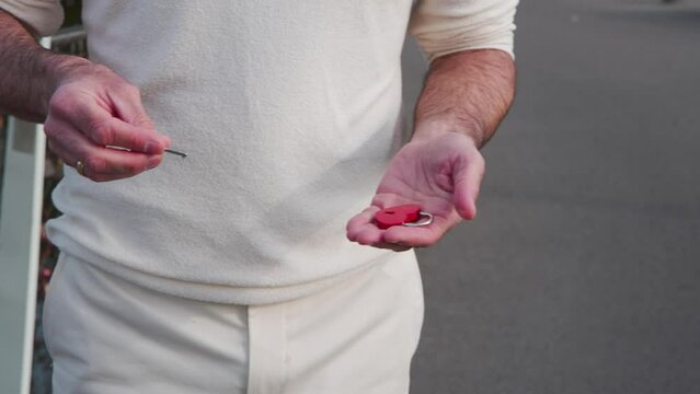Man holding red heart padlock and key to lock on lock bridge fence.