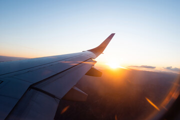 Naklejka na ściany i meble Looking at the sunset through the airplane window
