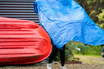 woman folding up a tarp at a campground in australia. camping tant and tarp while caravaning and...