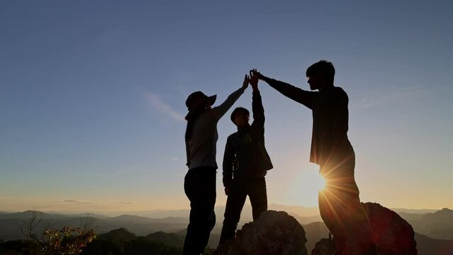 silhouette of people raise their hands up to the sky and join their palms together in the bright summer sun. Strengthening team spirit by joining hands together. teamwork, business success.