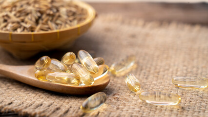 Capsule rice barn oil in wooden spoon with cold press rice barn oil. Rich in good fats, vitamin E,...