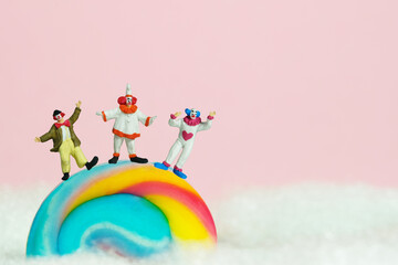 Miniature people toy figure photography. Playground island above clouds. Group of clowns wearing...
