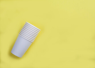 White paper disposable cups on a yellow background. View from above.Flat lay. Copy spaes