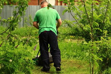 a man mows the grass with a lawn mower in the garden