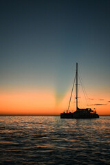 Sailboat in silhouette in front of a sunset on the Caribbean Ocean in Jamaica, Negril - orange, blue