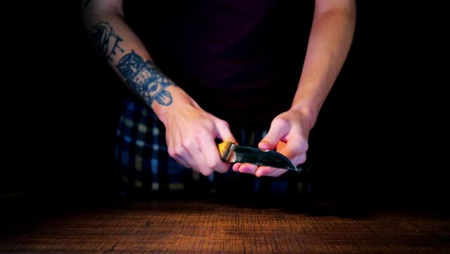 A man sharpens knives on a black background