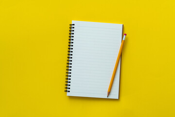 Blank notebook and a pen on yellow background