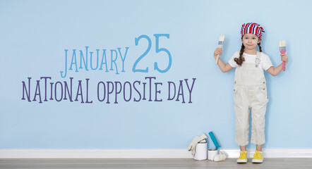 Little girl with paint brushes and text NATIONAL OPPOSITE DAY against light blue wall