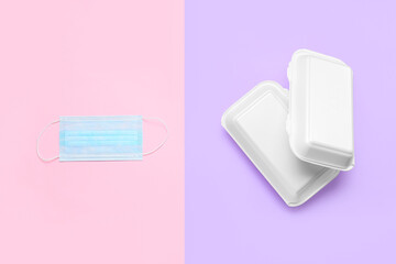 Takeaway boxes and medical mask on color background