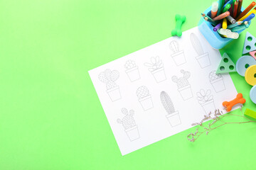 Coloring page, felt-tip pens, pencils, toys and flower on green background