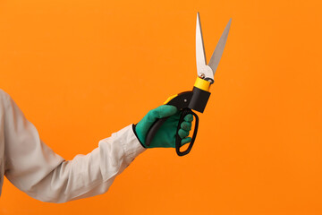Female gardener with pruner on orange background