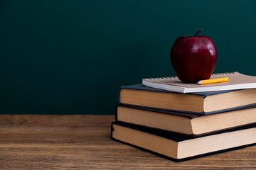 Red apple on book in front of the blackboard