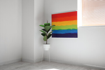 Houseplant and painting of LGBT flag hanging on light wall in room