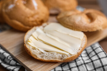 Delicious kaiser rolls with butter on wooden board