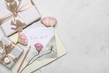 Composition with card, gift boxes, notebook and eustoma flowers on light background