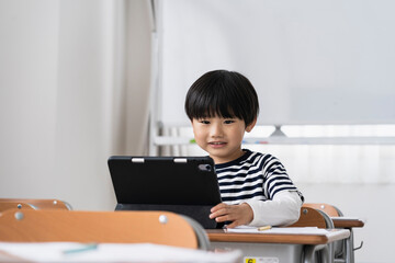 教室でタブレットPCを見る日本人小学生の男の子