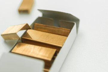 Stationery staples for stapler in a box on a white background. A set of new staples for fastening sheets of paper with a stapler. Selective focus