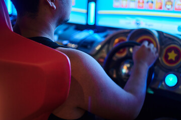 Young man driving funny arcade game without t-shirt and short beard