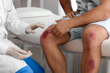 Doctor examining man with bruises in clinic