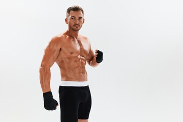 Fototapeta na wymiar Man athletic bodybuilder poses in boxing gloves with nude torso abs in full-length background, boxing and martial arts. Advertising, sports, active lifestyle, competition, challenge concept. 