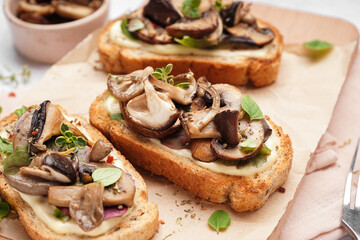 Wooden board of tasty toasts with cream cheese and mushrooms on light background, closeup