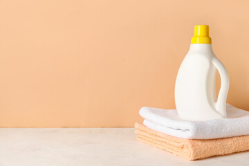 Laundry detergent with towels on table against beige background